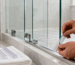Professional installing a clear shower door seal on a frameless glass shower door